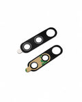 Two black plastic replacement camera lens protectors or lens pieces on a plain white background, one showing the outer surface and the other showing the inner side with adhesive backing and a piece of tape.