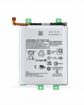 A replacement Li-Ion battery for a smartphone, featuring a white printed label with regulatory text and symbols, green mounting clips on the top and bottom, and an orange flex cable connector on the left, shown against a plain white background.