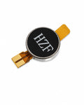 A circular electronic component with a black face featuring the white text 'HZF', surrounded by a silver metal rim, with gold-plated flexible circuitry leads extending from the sides, set against a plain white background.