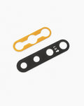 Two flat metal hardware pieces on a light gray background: one gold/yellow and one black with white 'LS' markings and arrow, both shown diagonally.